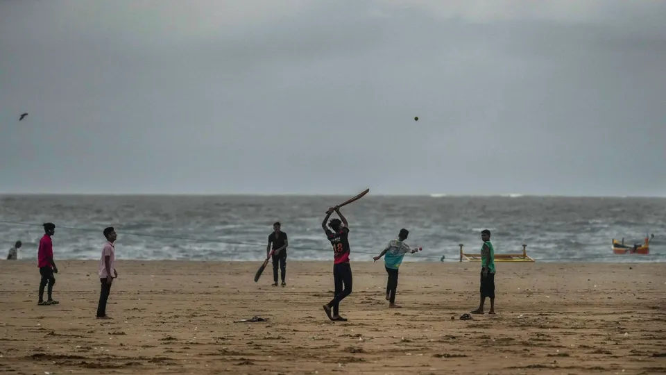 Youngsters play cricket on the beach, in Mumbai