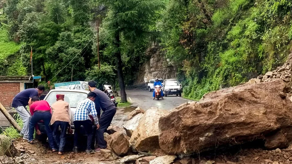 People try to move a car after a road got blocked due to landslide following rains, in Shimla, Monday, July 22, 2024.