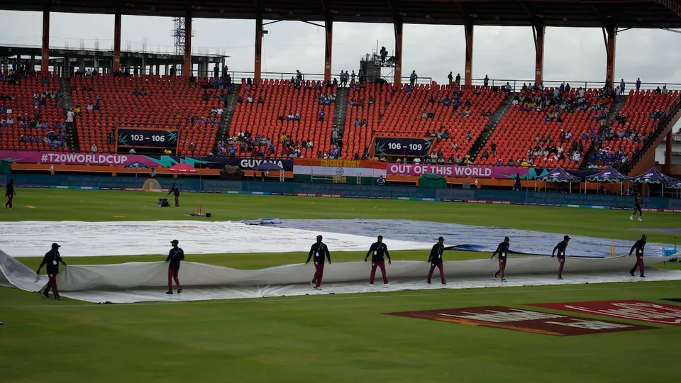 Groundsmen move the covers after wet outfield delayed the toss for the ICC Men's T20 World Cup second semifinal cricket match between England and India at the Guyana National Stadium in Providence, Guyana, Thursday, June 27, 2024.