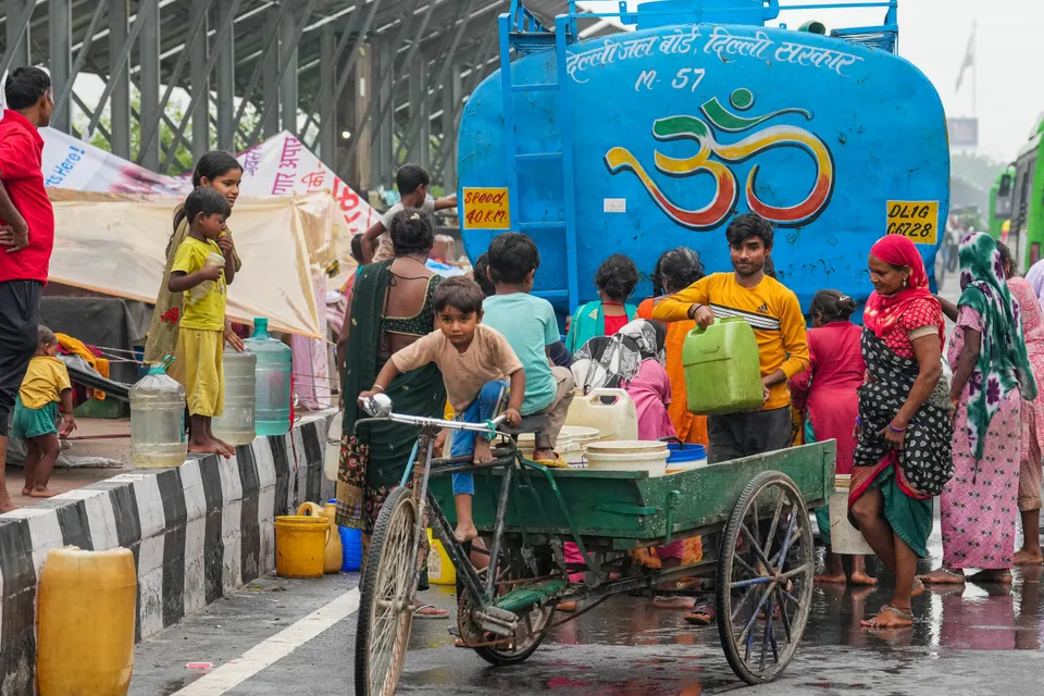 People from low-lying areas around the Yamuna river collect drinking water near their makeshift tents along a road, in New Delhi