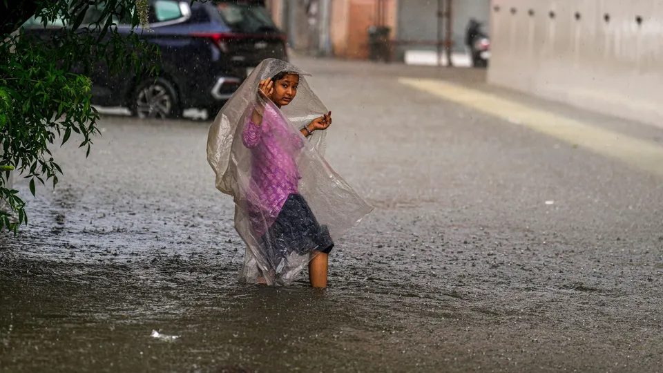 A young woman on a waterlogged road as the India Meteorological Department (IMD) has issued an red alert, predicting heavy rains, in Chennai, Tuesday, Oct. 15, 2024.