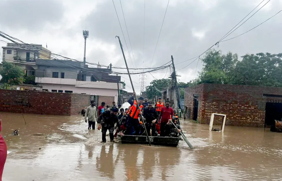 Rescue team members shift locals stuck near flooded Rishi Colony to a safer place after water level of Badi Nadi rose due to heavy monsoon rains, in Patiala