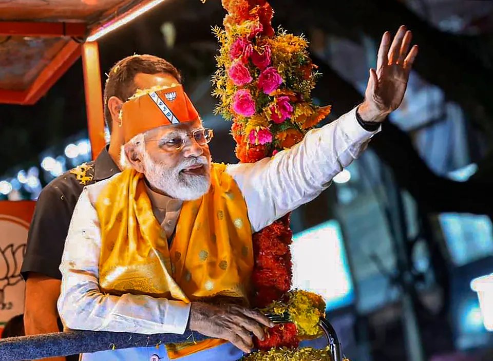 Prime Minister Narendra Modi waves at supporters during an election campaign roadshow in support of BJP candidates ahead of Assembly polls