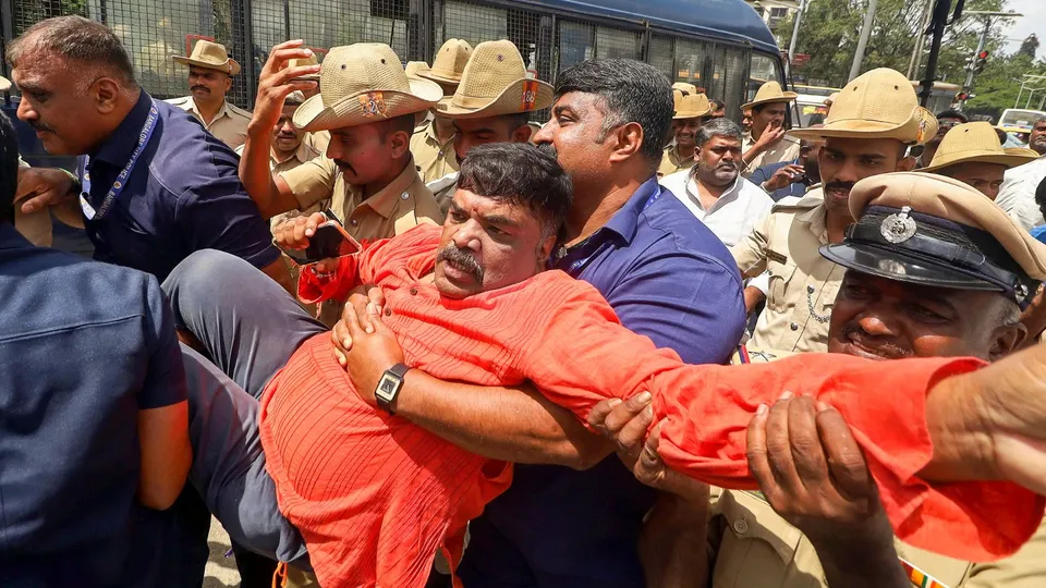 Police personnel detain an activist amid protests over the clashes that broke out between two groups during a Ganpati procession in Nagamangala town of Karnataka's Mandya district, in Bengaluru, Friday, Sept. 13, 2024.