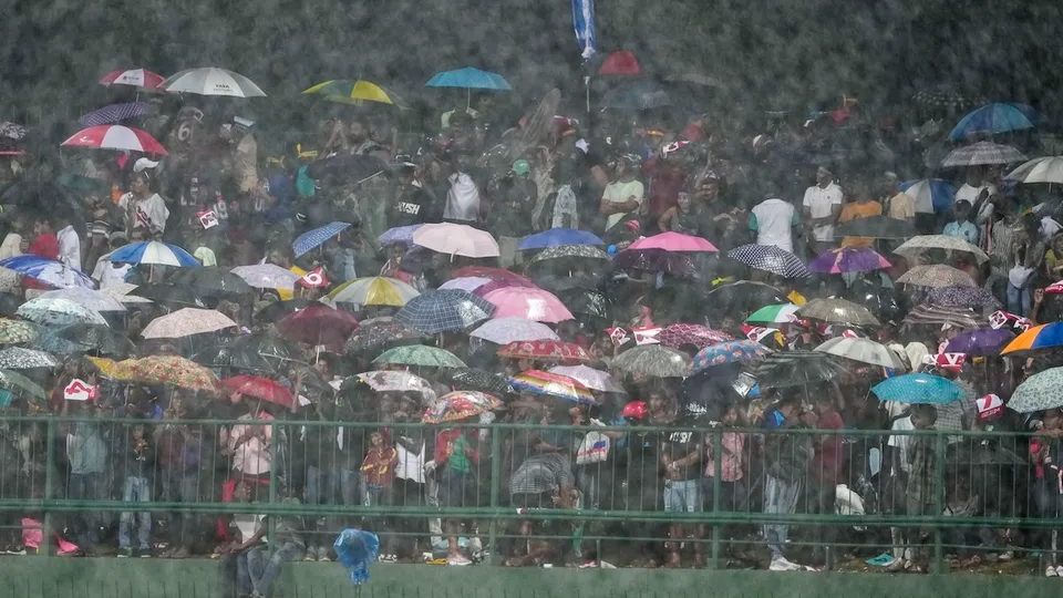 Spectators hold umbrellas as it rains during the second T20 International cricket match between India and Sri Lanka, at the Pallekele International Cricket Stadium, in Pallekele, Sunday, July 28, 2024.