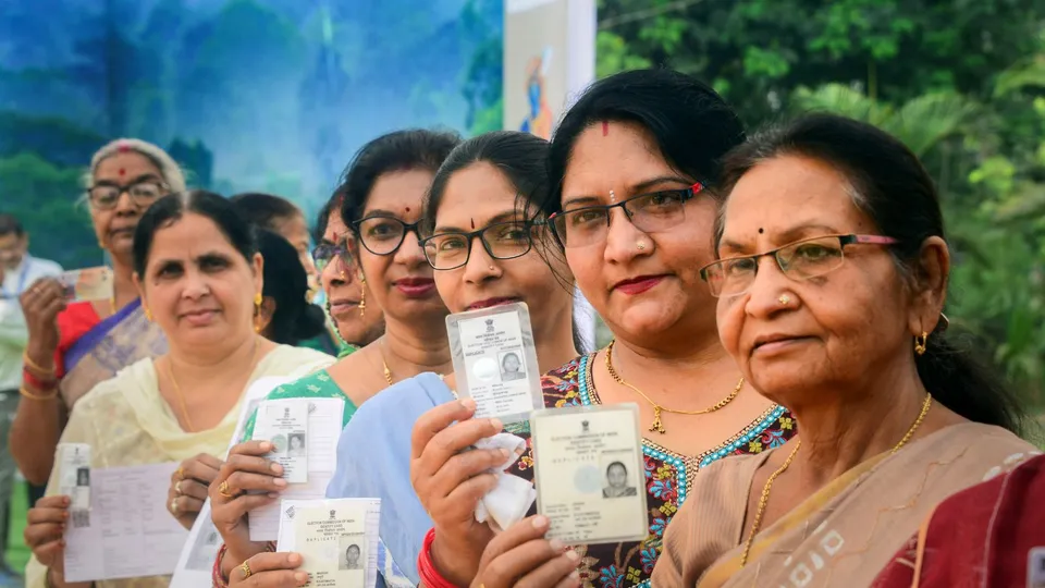 Voters show their identification cards as they wait in queues at a polling station to cast their votes for the first phase of Lok Sabha elections, in Bastar district, Friday, April 19, 2024
