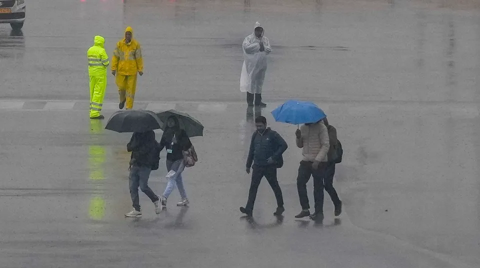 Pedestrians during rain on a cold and foggy winter morning, in New Delhi