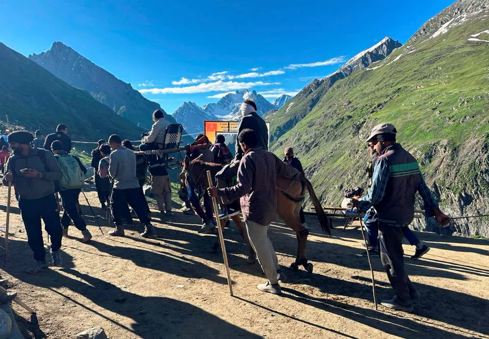 Porters carry a pilgrim at Brarimarg enroute to the holy Amarnath shrine, in Baltal, J & K, Thursday.jpg