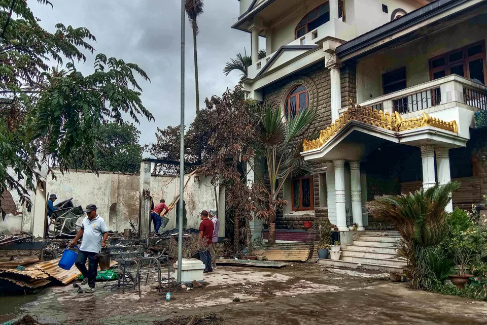 Workers attempt to salvage burnt items at Union Minister of State for External Affairs R K Ranjan Singh’s residence in Imphal