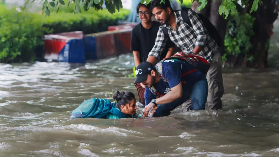 People help a pedestrian who fell on a flooded road after heavy monsoon rains, at ITO in New Delhi, Tuesday, Aug. 20, 2024