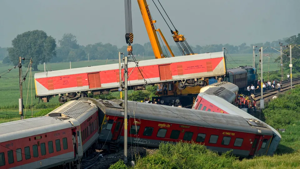A crane removes a derailed coach of North East Express from the track a day after its derailment near Raghunathpur railway station in Buxar district