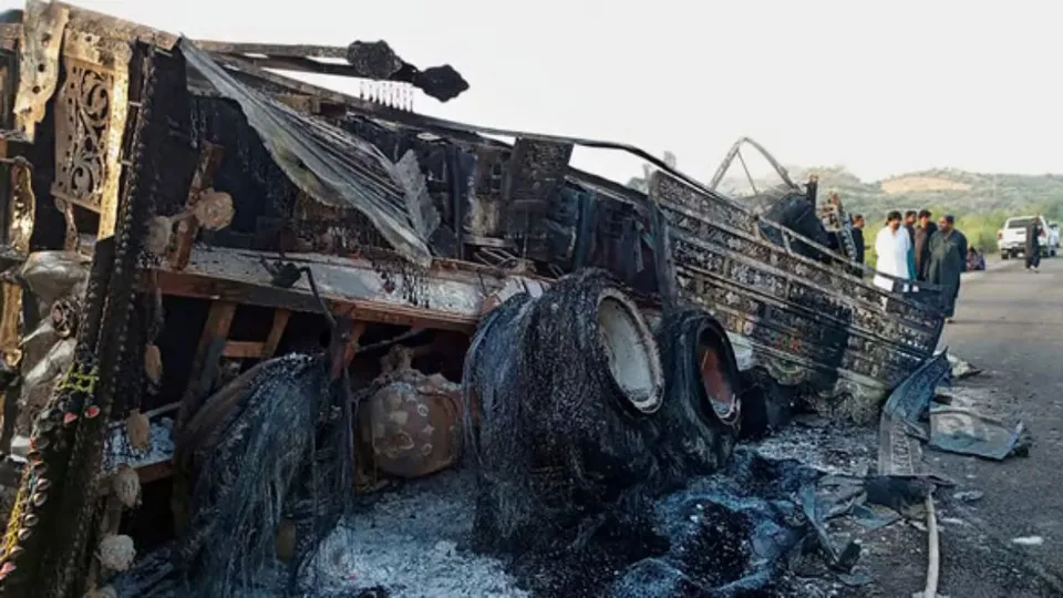 People look burnt vehicles, torched by gunmen after killing passengers, at a highway in Musakhail, a district in Baluchistan province in southwestern Pakistan, Monday