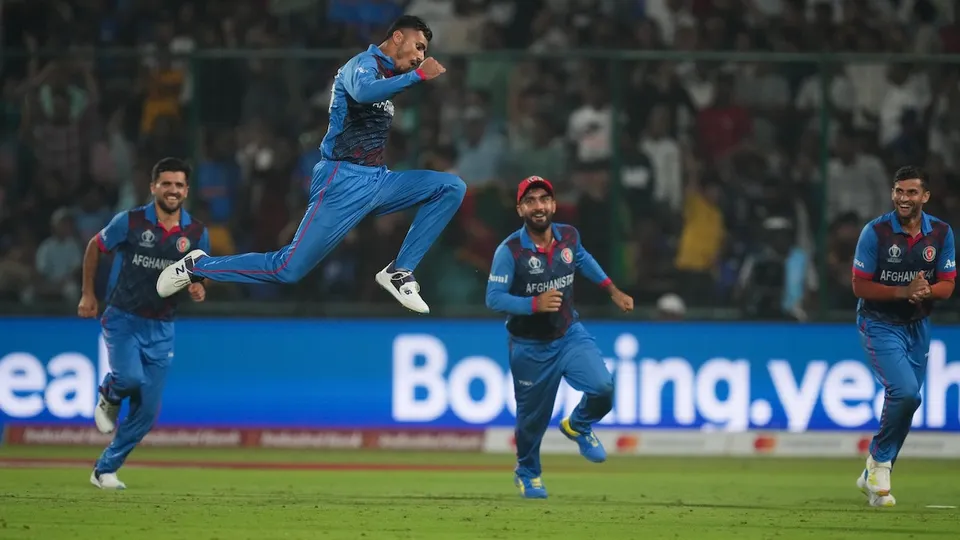 Afghanistan's Mujeeb Ur Rahman with teamamtes celebrates the wicket of England's Chris Woakes during the ICC Men's Cricket World Cup 2023 match between Afghanistan and England, at Arun Jaitley Stadium in New Delhi, Sunday, Oct. 15, 2023.