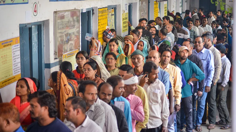 Voters wait in a queue at a polling station to cast their votes for the Madhya Pradesh Assembly elections, in Jabalpur