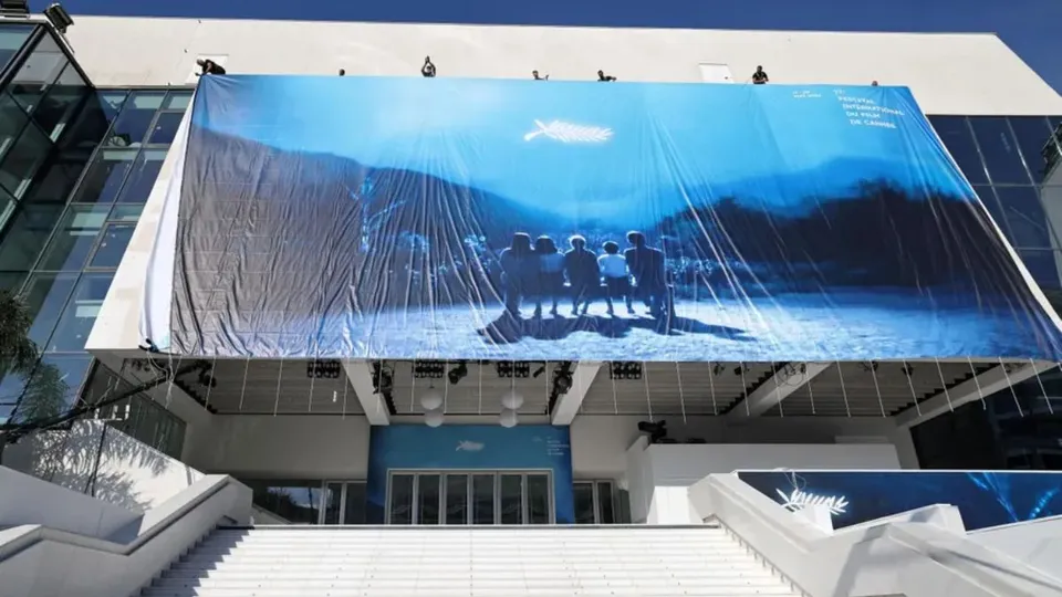 Workers install the official poster on the Palais de Festival ahead of the 77th annual Cannes Film Festival at on May 12, 2024 in Cannes, France.