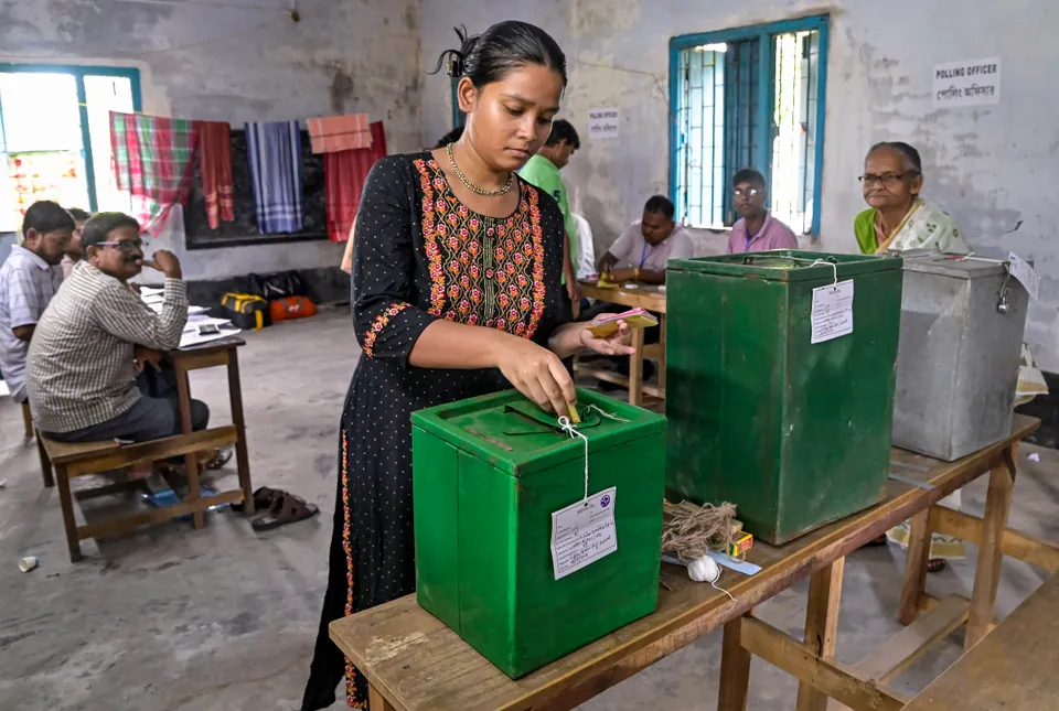 A woman drops a ballot paper while casting her vote for the panchayat elections