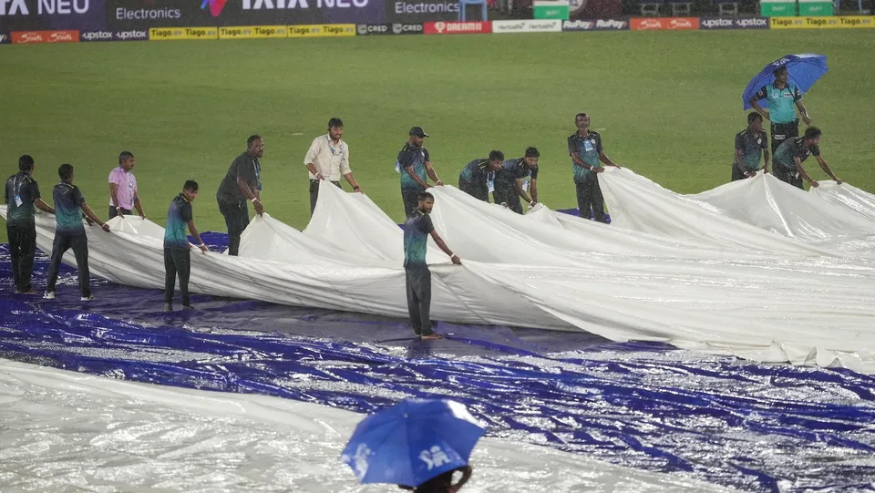 Groundsmen cover the pitch as it rains during the IPL 2023 cricket match between Gujarat Titans and Chennai Super Kings, at the Narendra Modi Stadium in Ahmedabad on May 29