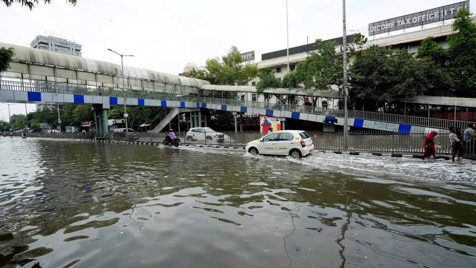 Commuters move through a waterlogged road at ITO, in New Delhi